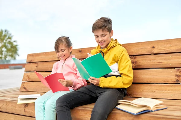 Crianças da escola com cadernos sentados no banco — Fotografia de Stock