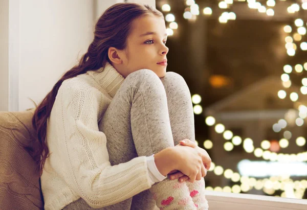 Noel de ev penceresinde oturan üzgün kız — Stok fotoğraf