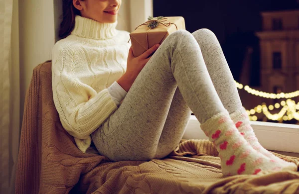 Girl with christmas gift sitting on window sill — Stock Photo, Image