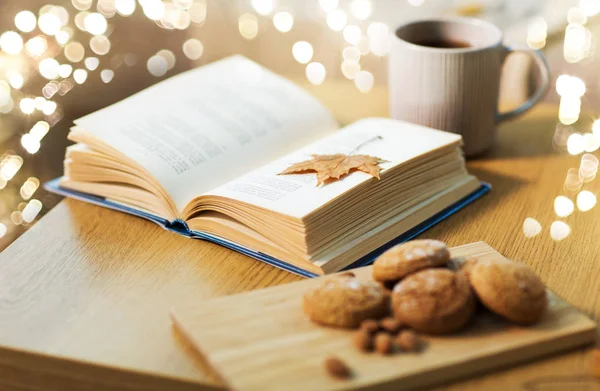 Livre avec feuille d'automne, biscuits et thé sur la table — Photo