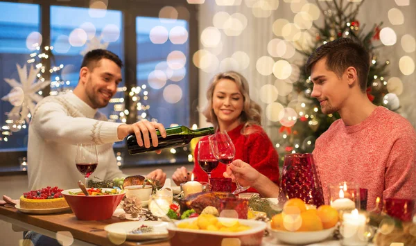 Amigos felizes bebendo vinho tinto na festa de Natal — Fotografia de Stock