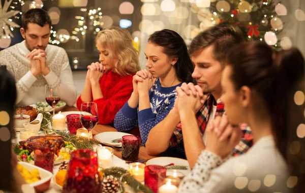 Friends having home christmas dinner and praying — Stock Photo, Image