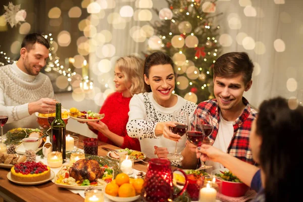 Amigos felizes bebendo vinho tinto na festa de Natal — Fotografia de Stock