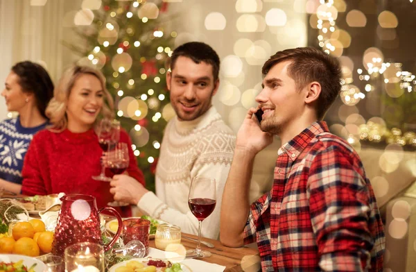 Mann telefoniert beim Weihnachtsessen mit Smartphone — Stockfoto