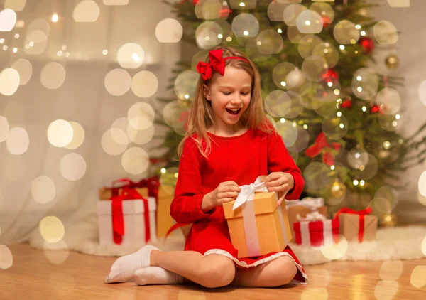 Улыбающаяся девушка с рождественским подарком дома — стоковое фото