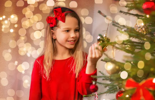 Lycklig flicka i rött dekorera julgran — Stockfoto