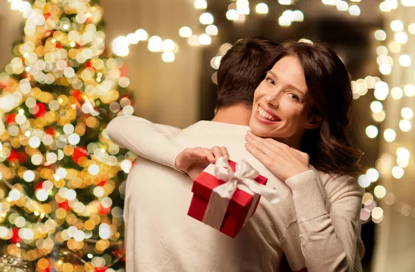 Szczęśliwy para z Boże Narodzenie prezent przytulanie w domu — Zdjęcie stockowe