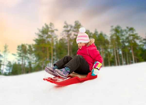 Ευτυχισμένο κοριτσάκι γλιστράει κάτω στο έλκηθρο το χειμώνα — Φωτογραφία Αρχείου