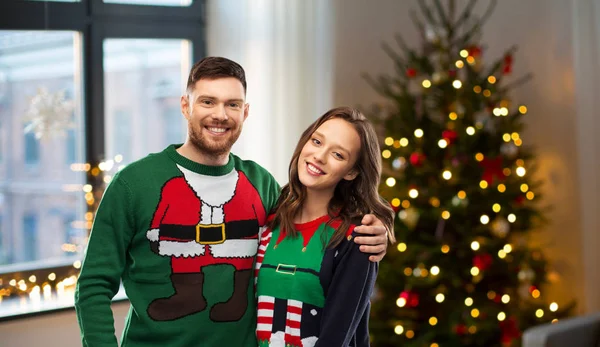 Feliz pareja en suéteres feos sobre árbol de Navidad —  Fotos de Stock