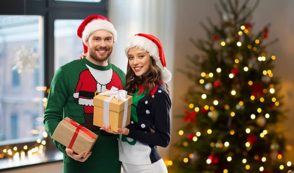 Casal feliz em camisolas com presentes de Natal — Fotografia de Stock