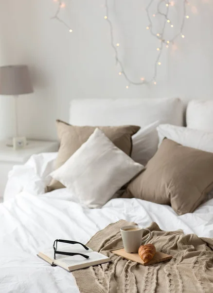 Coffee, croissant, blanket and book on bed at home — Stock Photo, Image