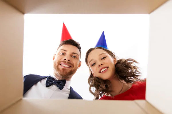 Couple in party hats opening birthday gift box — Stock Photo, Image