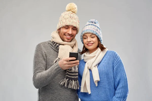 Pareja feliz en ropa de invierno con smartphone — Foto de Stock