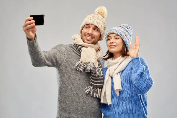 Пара в зимних шляпах делает селфи на смартфоне — стоковое фото