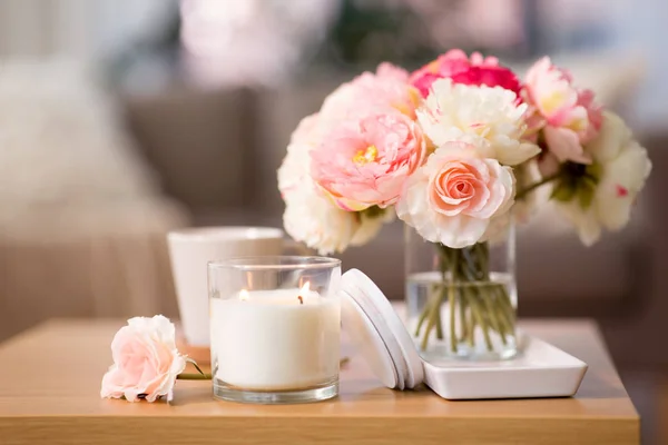 Burning candle and flower bunch on wooden table — Stock Photo, Image