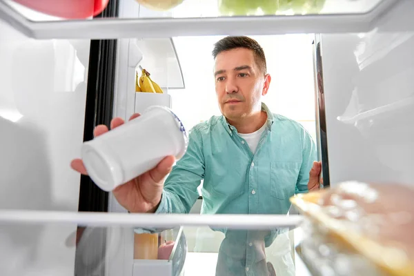 Мужчина берет еду из холодильника на кухне — стоковое фото