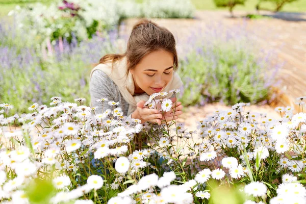 Donna felice profumando fiori di camomilla in giardino — Foto Stock