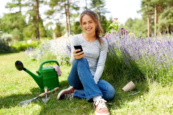 Donna con smartphone e attrezzi da giardino in estate — Foto Stock