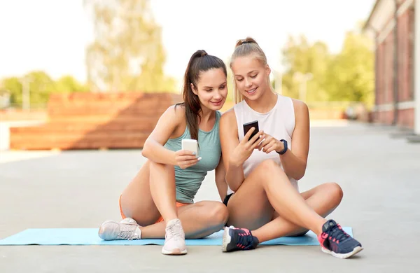 Mujeres deportivas o amigos con teléfono inteligente en la azotea — Foto de Stock