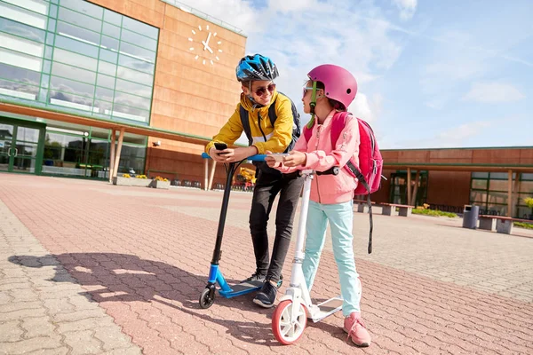 スマートフォンやスクーターを持つ学校の子供たち — ストック写真