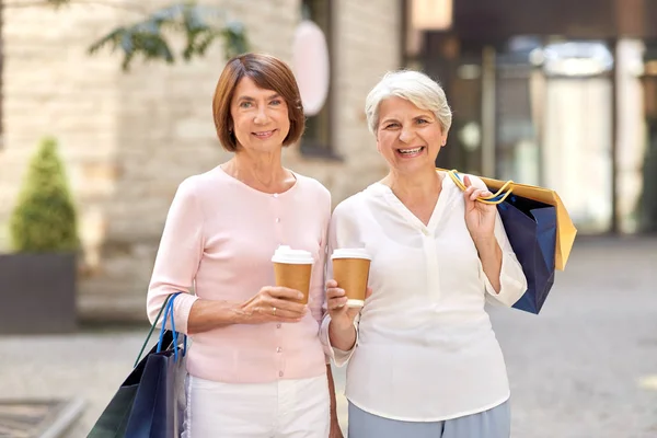 Пожилые женщины с сумками и кофе в городе — стоковое фото