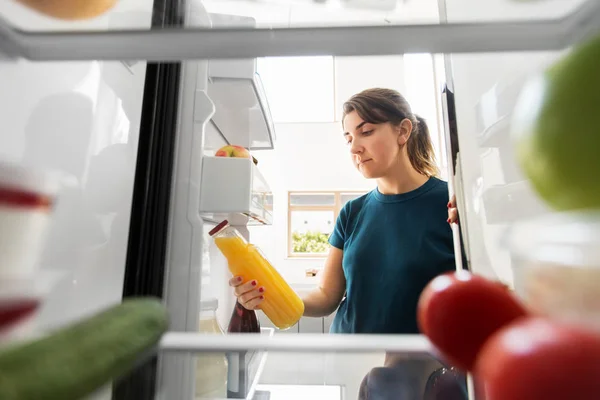 Kvinna tar flaska saft från kylskåp hemma — Stockfoto