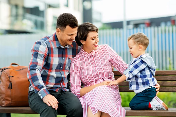 Família feliz sentado no banco de rua na cidade — Fotografia de Stock