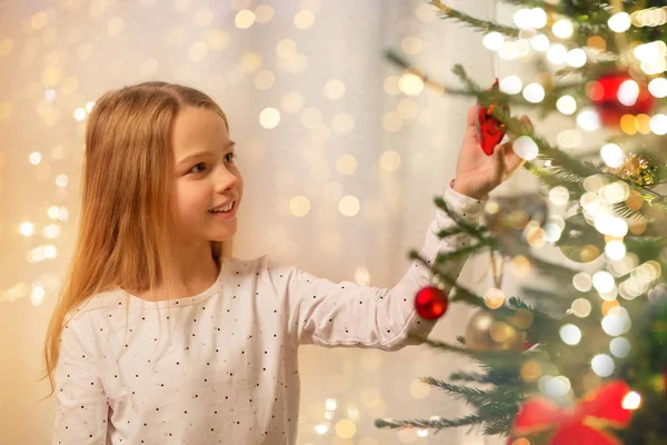 Chica feliz en vestido rojo decorando árbol de Navidad —  Fotos de Stock