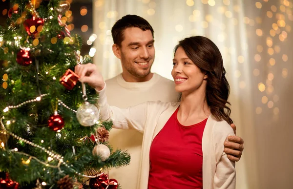 Happy couple decorating christmas tree at home — Stock Photo, Image