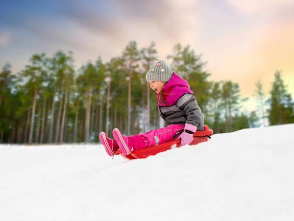 Glückliches kleines Mädchen rutscht im Winter auf Schlitten — Stockfoto