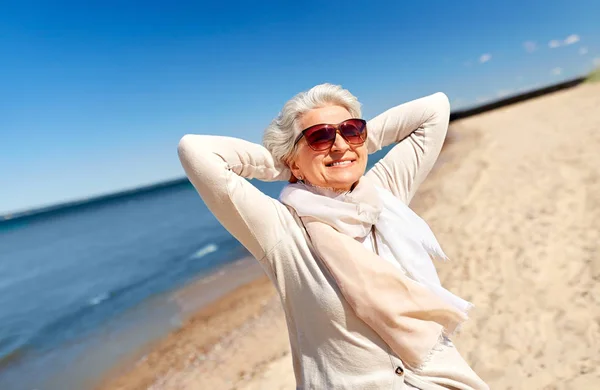 Портрет пожилой женщины в солнечных очках на пляже — стоковое фото
