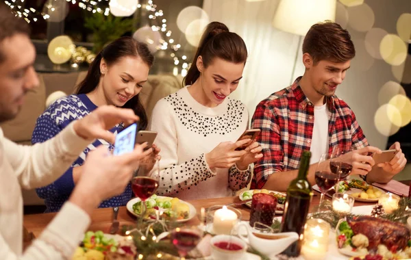 Друзья со смартфонами на рождественский ужин — стоковое фото