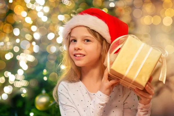 Leende flicka i tomte hatt med julklapp — Stockfoto