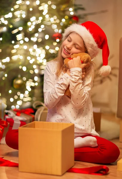 サンタ・ハットの笑顔の女の子とクリスマスプレゼント — ストック写真