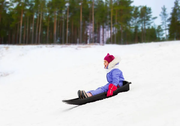 Glückliches kleines Mädchen rutscht im Winter auf Schlitten — Stockfoto