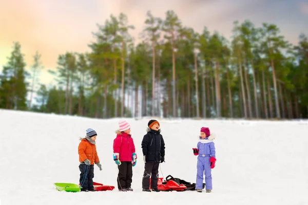 Petits enfants heureux avec des traîneaux en hiver — Photo