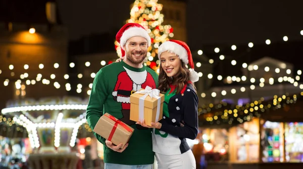 Happy couple with gifts at christmas market — Stock Photo, Image