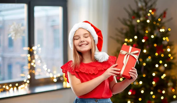 Chica en sombrero de santa con regalo de Navidad en casa —  Fotos de Stock