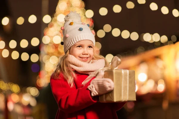 Lycklig tjej med presentförpackning på julmarknad — Stockfoto