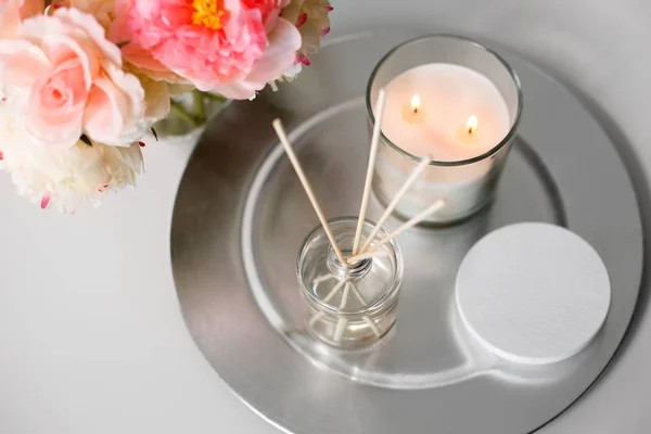 Aroma rákosí difuzor, svíčka a květiny na stole — Stock fotografie