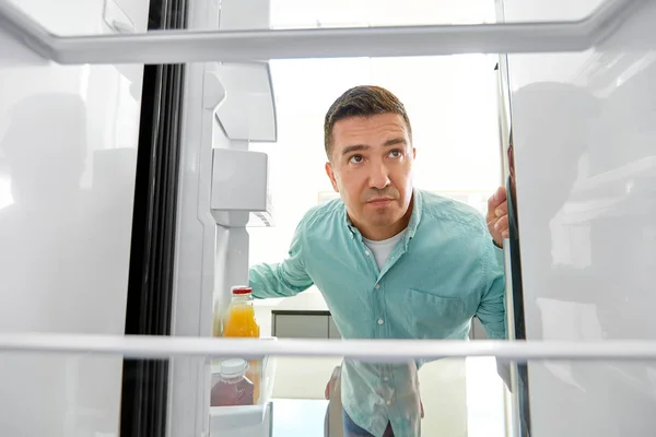 Homem procurando comida na geladeira vazia na cozinha — Fotografia de Stock