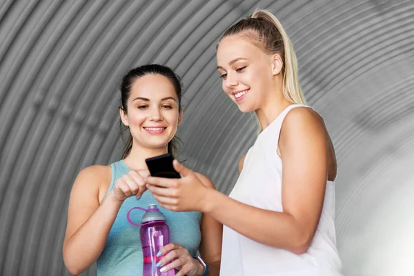 Women or female friends with smartphone and flask — Stock Photo, Image