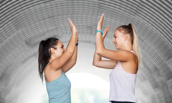 Mujeres felices con rastreadores de fitness haciendo high five — Foto de Stock