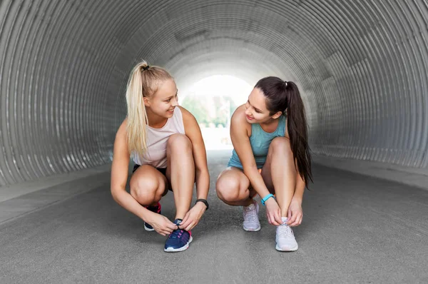 スポーティな女性や女性の友人は靴のレースを結ぶ — ストック写真
