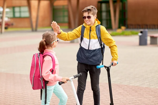 Happy school children with backpacks and scooters — Stock Photo, Image