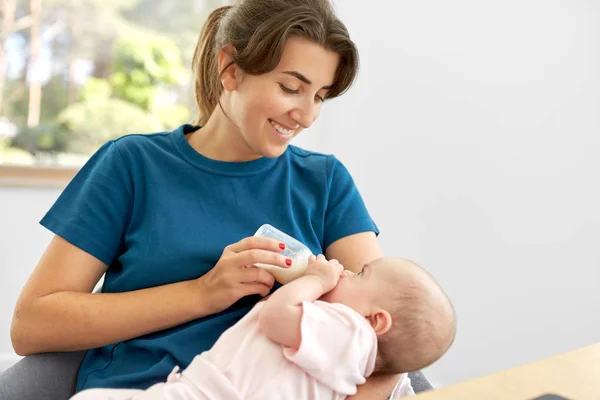 Mother feeding baby daughter with milk formula — Stock Photo, Image