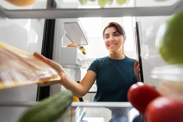 Lycklig kvinna som tar mat från kylskåp hemma — Stockfoto