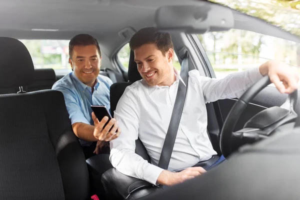 Passager masculin montrant smartphone au conducteur de voiture — Photo