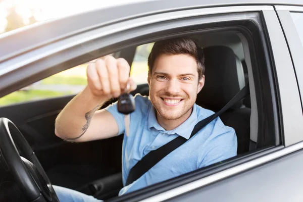 Sorridente homem ou motorista com chave sentado no carro — Fotografia de Stock