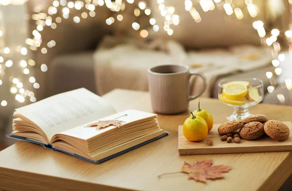 Kirja, sitruuna, tee ja evästeet pöydällä kotona — kuvapankkivalokuva